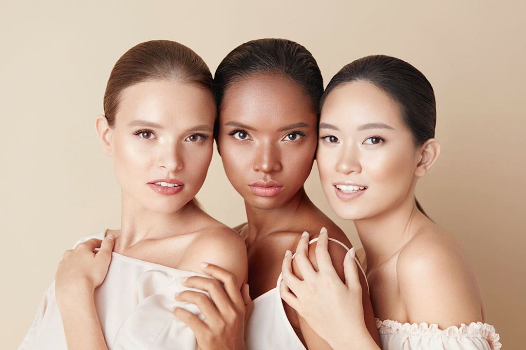 3 women - Beauty. Portrait Of Diversity Models. Mixed Race, Asian And Caucasian Girls Hugs Each Other And Looking At Camera. Different Ethnicity Women With Nude Makeup And Perfect Glowing Skin.